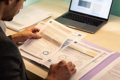 Analist onderzoekt Europese MiCA-vergunningen aan een bureau met documenten